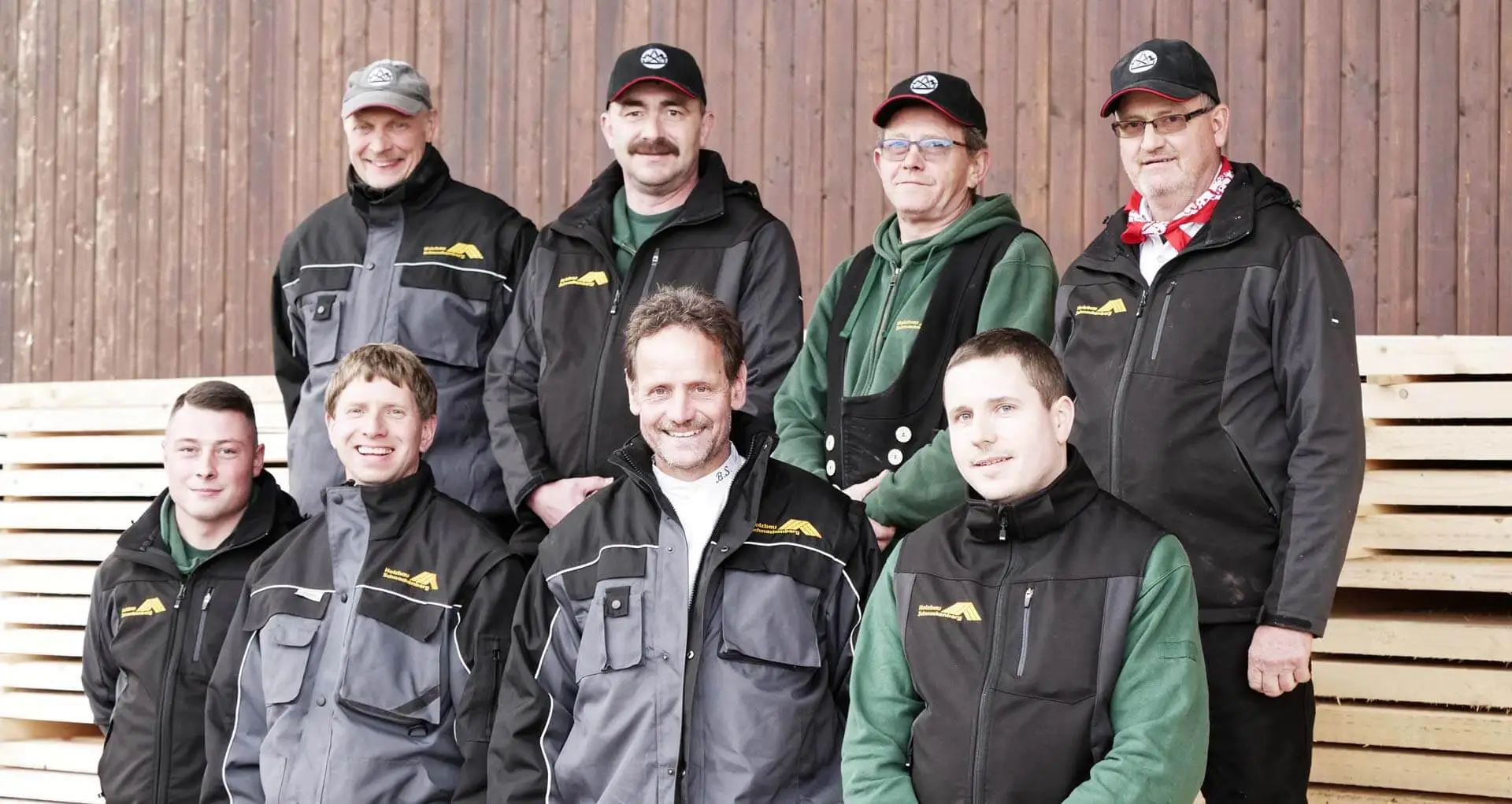 Foto von Mitarbeitern der Schnackenberg Holzbau GmbH mit Arbeitsjacken und Westen